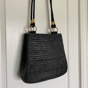 Black woven straw bag with gold ring accents.